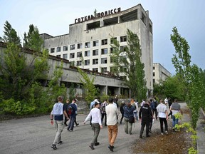 Visitors walk in the ghost city of Pripyat during a tour in the Chernobyl exclusion zone on June 7, 2019.