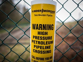 A sign warning of an underground petroleum pipeline is seen on a fence at Kinder Morgan's facility where work is being conducted in preparation for the expansion of the Trans Mountain Pipeline, in Burnaby, B.C., on April 9, 2018. A former Liberal environment minister is urging Prime Minister Justin Trudeau's cabinet to reject the Trans Mountain pipeline expansion because he says there is no economic basis for the project.