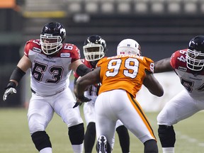 Jon Gott (63) and J'Micheal Deane (64) of the Stampeders prepare to block Jabar Westerman (99) of the Lions during the CFL Western Division Final football game at BC Place in Vancouver, B.C. November 18, 2012. Bob Frid/STR/QMI Agency