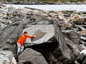 An image of a woman putting her hand in the Devil's Heart on Fogo Island, Newfoundland.
