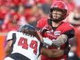 Calgary Stampeder QB Bo Levi Mitchell is pressured by Ottawa Redblacks J.R. Tavai during CFL action in Calgary on Saturday, June 15, 2019.