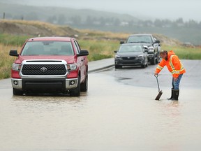 A consulting engineer for the developer in the Heartland district in Cochrane opens a storm drain on Friday, June 21, 2019, during heavy rain.