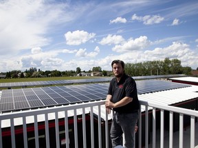 Greg Robinson, Raymond's economic development co-ordinator, poses in front of solar panels on top of a municipal building in the town.
