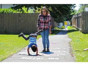 Harden Marcil, 5, and his mom Lise have some fun with a pavement 'mirror me' game along one of the newly revitalized Marlborough catwalks on Saturday. Photo by Gavin Young/Postmedia.