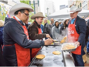 Premier Jason Kenny, right, and Mayor Naheed Nenshi serve pancake at First Flip, the first pancake breakfast of the Stampede season, on Stephen Avenue on Calgary on Thursday, July 4, 2019.