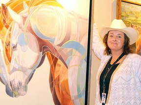 Artist Carolyn Sinclair poses for a photograph in front of one of her many equine abstract paintings on display in the Western Showcase located in the BMO Centre on Sunday, July 7, 2019. Brendan Miller/Postmedia
