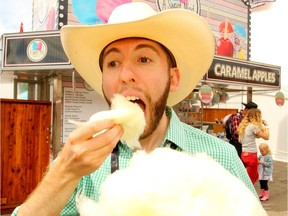 Postmedia reporter Sammy Hudes tries a "Pickle Cotten Candy" on the midway at the Calgary Stampede on Wednesday, July 10, 2019. Brendan Miller/Postmedia