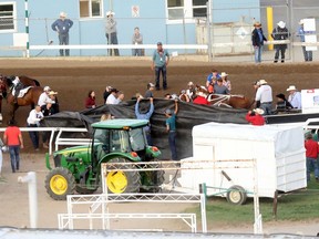 Officials tend to a crash during heat 7 of the Rangeland Derby chuckwagon races at the Calgary Stampede on Thursday, July 11, 2019.