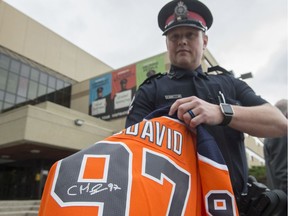 Cst. Derek Burns with the Edmonton Police Service holds a Connor McDavid jersey with a fake signature on July 18, 2019.