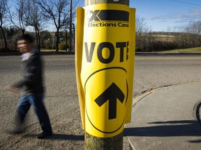 A voter walks past a sign directing voters to a polling station for the Canadian federal election in Cremona, Alta., Oct. 19, 2015.