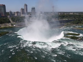 The town of Niagara Falls, Canada is seen past a cloud of mist rising over Horseshoe Falls, the largest of the Niagara Falls on June 4, 2013 across from Niagara Falls, New York.