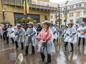 Chinook Country Line Dancers perform under the rain at First Flip, the first pancake breakfast of the Stampede season, on Stephen Avenue on Thursday, July 4, 2019.