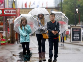 From left: Claire, Alina and Max Leavitt were prepared for the rain at  sneak-a-peek at the Calgary Stampede on Thursday, July 4, 2019.