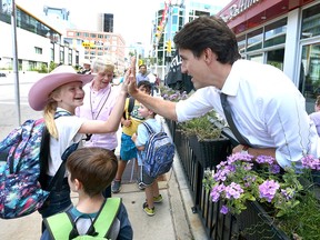 Prime Minister Justin Trudeau greets a group of school aged kids as they pass by during Trudeau's stop at The Beltliner Diner in downtown Calgary on Friday, July 12, 2019.