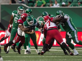 Saskatchewan Roughriders quarterback Cody Fajardo (7) scrambles with the ball while under pressure from the Calgary Stampeders during a game at Mosaic Stadium. Photo by Brandon Harder/Postmedia.