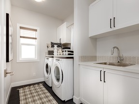 This laundry room by Excel Homes boasts a laundry sink and ample cabinetry and storage.