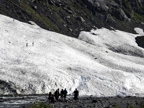 People hike on the Byron Glacier while others stand along a creek on July 4, 2019 near Portage Lake in Girdwood, Alaska. Alaska is bracing for record warm temperatures and dry conditions in parts of the state.