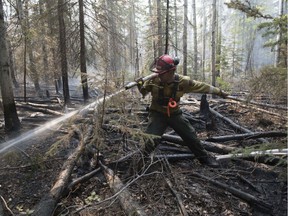 A firefighter extinguishs hotspots beside Highway 35 just south of the town of High Level on Friday, May 25, 2019. Nearly 400 firefighters, 28 helicopters, and eight air tankers continue to battle northwest Alberta wildfires. (photography by Chris Schwarz/Government of Alberta) --- Begin Additional Info --- Wildland fire crews tackle hotspots in the forest near High Level Saturday, May 25, 2019. Crews are gearing up for Sunday, when the wind is expected to shift and start fanning the flames back toward town. ORG XMIT: POS1905252000224332