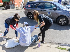 Jacqueline Jerran, right, and Chelsey Cascadden, full-time DOAP members, help a homeless person outside Alpha House in Calgary on Thursday, August 15, 2019.
