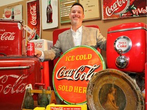 Kevin King, Owner of Hall's Auction Services Ltd. poses for a photo among dozens of Coca-Cola collectables that are up for auction.