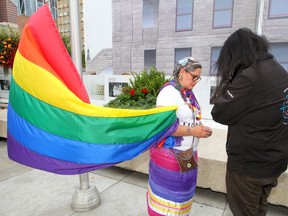 Michelle Robinson and Spiritriver Striped Wolf perform a smudge ceremony at Calgary City Hall during a flag raising event to kick off Pride Week.