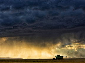 A storm rolls in over a combine in southern Alberta. Net farm incomes fell by nearly 21 per cent last year, one of the largest year-over-year decreases ever recorded in Canada.