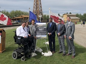 MP Kent Hehr, Heritage Park CEO Alida Visbach and Minister Prasad Panda pose for a photo with members of the park's board of directors in front of the Dingman well on Friday.