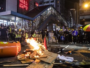 Fire burns as demonstrators stand off against riot police on Percival Street during a protest in the Causeway Bay district of Hong Kong, China, on Sunday, Aug. 4, 2019. Hong Kong riot police broke up protests blocking roads in Causeway Bay and fired tear gas in the popular shopping district, capping a weekend of violent demonstrations across the city that marked the ninth week of civil unrest in the Asian financial capital. Photographer: Justin Chin/Bloomberg ORG XMIT: 775384719