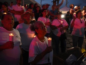 A group of people attend a vigil at a memorial four days after the mass shooting at a Walmart store in El Paso, Texas.