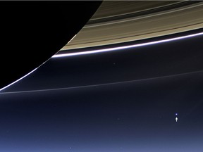 TOPSHOTS In this NASA handout image taken on July 19, 2013  the wide-angle camera on NASA's Cassini spacecraft has captured Saturn's rings and planet Earth and its moon in the same frame. Earth, which is 1.44 billion kilometres away in this image, appears as a blue dot at centre right; the moon can be seen as a fainter protrusion off its right side. An arrow indicates their location in the annotated version. It is only one footprint in a mosaic of 33 footprints covering the entire Saturn ring system (including Saturn itself).  At each footprint, images were taken in different spectral filters for a total of 323 images: some were taken for scientific purposes and some to produce a natural colour mosaic.  This is the only wide-angle footprint that has the Earth-moon system in it. The images were obtained with the Cassini spacecraft wide-angle camera at a distance of approximately 1.212 million kilometres from Saturn, and approximately 1.445858 billion kilometres from Earth. Image scale on Saturn is 69 kilometres per pixel; image scale on the Earth is 86,620 kilometres per pixel.  The illuminated areas of neither Earth nor the moon are resolved here. Consequently, the size of each "dot" is the same size that a point of light of comparable brightness would have in the wide-angle camera.