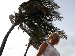 A woman walks by palm trees whipped by winds from Hurricane Dorian on September 2, 2019 in Vero Beach, Florida.