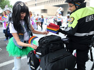 A EMS paramedic gets a rainbow flag added to his bike as  the Calgary Pride parade went through downtown Calgary on Sunday September 1, 2019.