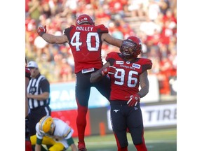 Calgary Stampeders Chris Casher and Nate Holley celebrate a sack on Edmonton Eskimos QB Trevor Harris to secure the win on the last play in second-half CFL action at McMahon stadium in Calgary on Saturday, Aug. 3. File photo by Darren Makowichuk/Postmedia.