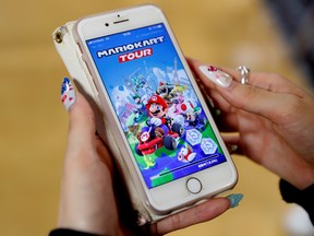 A woman shows the mobile game Mario Kart Tour on her smartphone.