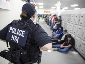 This image released by the US Immigration and Customs Enforcement (ICE) shows a Homeland Security Investigations (HSI) officer guarding suspected migrants on August 7, 2019.