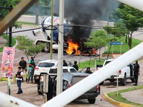 Cartel gunmen are seen near a burning truck during clashes with federal forces following the detention of Ovidio Guzman, son of drug kingpin Joaquin "El Chapo" Guzman, in Culiacan, Sinaloa state, Mexico October 17, 2019.