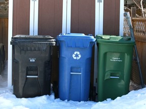 A City of Calgary black bin used to collect garbage, a blue recycling bin and a green bin for ffood and yard waste, are shown in an alley in Acadia in Calgary on Saturday, March 10, 2018. Jim Wells/Postmedia