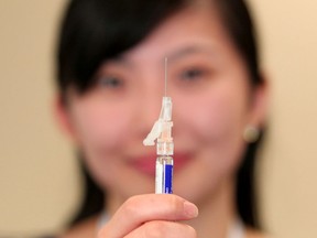 RN Diana Huynh holds a flu shot at the South Calgary Health Centre.