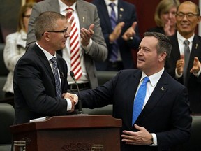 Alberta Finance Minister Travis Toews, left, shakes hands with Premier Jason Kenney after Toews delivered his budget speech at the Alberta legislature in Edmonton on Thursday, Oct. 24, 2019.
