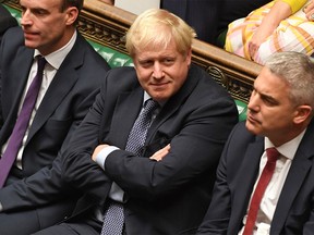 A handout picture released by the UK Parliament shows Britain's Prime Minister Boris Johnson (C) smiling in the House of Commons in London on October 19, 2019, during a debate on the Brexit deal. - A day of high drama in parliament on Saturday saw lawmakers vote for a last-minute amendment to the deal that could force the government to seek to extend the October 31 deadline to leave. (Photo by JESSICA TAYLOR / UK PARLIAMENT / AFP)
