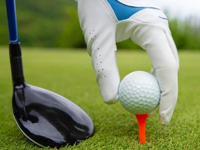 Hand putting golf ball on tee in golf course