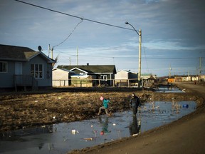 Indigenous children play in water-filled ditches in Attawapiskat, Ont. on April 19, 2016.