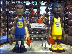 Statues of NBA players Stephen Curry of the Golden State Warriors, left, and Lebron James of the Los Angeles Lakers hold Chinese flags in the entrance of an NBA merchandise store in Beijing, Tuesday, Oct. 8, 2019. Chinese state broadcaster CCTV announced Tuesday it will no longer air two NBA preseason games set to be played in the country.