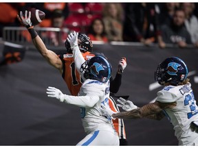The B.C. Lions' Bryan Burnham makes a one-handed catch in the endzone to score his second touchdown as Toronto Argonauts; Trumaine Washington, front left, and Anthony Covington, right, defend during first half CFL football action in Vancouver on Saturday, Oct. 5.