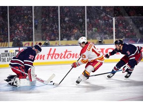 Oct 26, 2019; Regina, Saskatchewan, CAN; Winnipeg Jets goaltender Connor Hellebuyck (37) blocks a shot byy Calgary Flames forward Johnny Gaudreau (13) during the first period of the 2019 Heritage Classic outdoor hockey game at Mosaic Stadium. Mandatory Credit: Anne-Marie Sorvin-USA TODAY Sports ORG XMIT: USATSI-405162