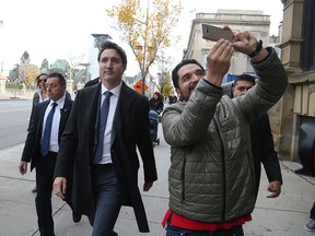 A bystander takes a selfie as Prime Minister Justin Trudeau walks to a news conference on Oct. 23, 2019 in Ottawa.