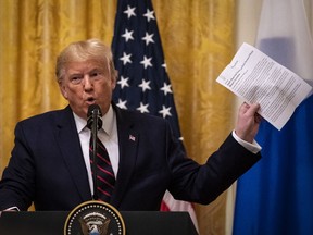 U.S. President Donald Trump holds up a New York Times article during a news conference with Sauli Niinisto, Finland's president, not pictured, in the East Room of the White House in Washington, D.C., U.S., on Wednesday, Oct. 2, 2019.