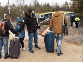 A family claiming to be from Colombia gets set to cross the border into Canada from the United States as asylum seekers on Wednesday, April 18, 2018 near Champlain, New York.