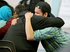 A young man gets a hug from a friend during talk of recent events. In the wake an epidemic of suicide attempts in Attawapiskat - including 11 young people last Saturday and a foiled suicide pact earlier this week - this remote Ontario reserve of 2,000 people declared a state of emergency over the weekend.  Today (April 13, 2016), Ontario's Minister of Health, Eric Hoskins, arrived on the reserve, along with Tracy MacCharles (Minister of Children and Youth) and Chief of the Assembly of First Nations, Perry Bellegarde, to hatch out solutions. They include an immediate two million dollars in emergency funding, plans to build a youth centre and other long-term strategies.  (JULIE OLIVER/POSTMEDIA) ORG XMIT: POS1604131656562849
