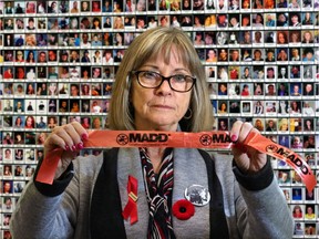 Denise Dubyk with MADD Calgary stands in front of a memorial wall to Canadian victims of impaired drivers at the launch of the annual Project Red Ribbon campaign to prevent impaired driving over the holiday season.